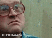 A Man Wearing Glasses Is Making A Funny Face And Looking At The Camera . GIF