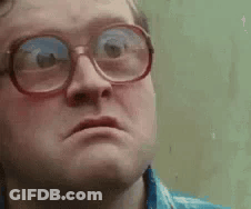 A Man Wearing Glasses Is Making A Funny Face And Looking At The Camera . GIF