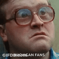A Man Wearing Glasses Is Making A Funny Face With The Words Michigan Fans Written On His Face . GIF