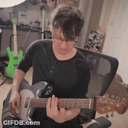 Man With Glasses Playing Guitar With B On Neck GIF
