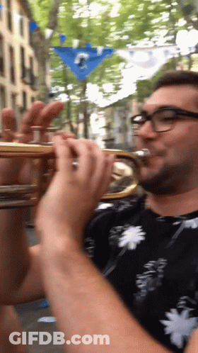 A Man Wearing Glasses Is Playing A Trumpet In A Blurry Photo GIF