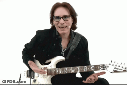 A Man Wearing Glasses Is Playing A White Guitar With The Letters Ibanez On The Neck GIF