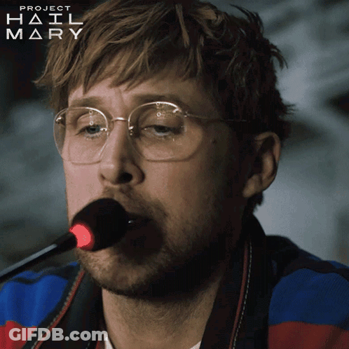 A Man Wearing Glasses Is Singing Into A Microphone With Project Hail Mary Written On The Bottom Right GIF