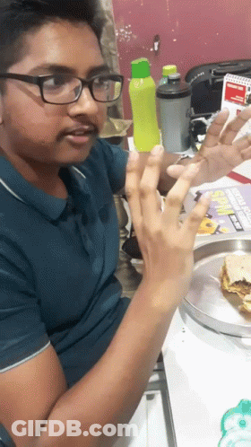 A Man Wearing Glasses Is Sitting At A Table With A Plate Of Food And A Sign That Says Subway GIF