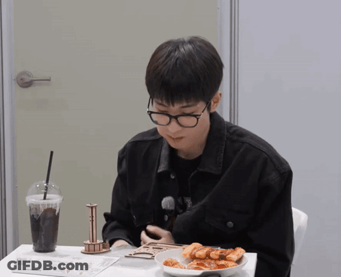 A Man Wearing Glasses Is Sitting At A Table With A Plate Of Food GIF