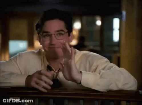 A Man Wearing Glasses Is Sitting At A Table With His Hand On His Face . GIF
