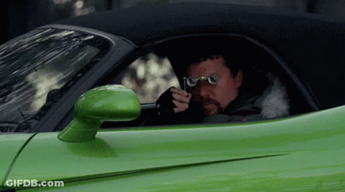 A Man Wearing Glasses Is Sitting In A Green Sports Car GIF