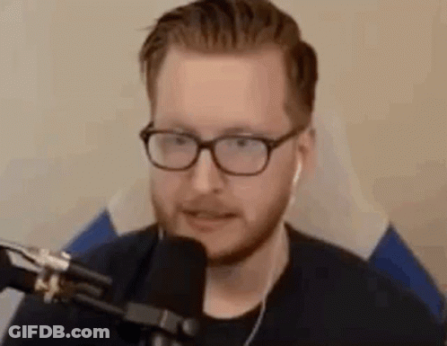 A Man Wearing Glasses Is Sitting In Front Of A Microphone . GIF