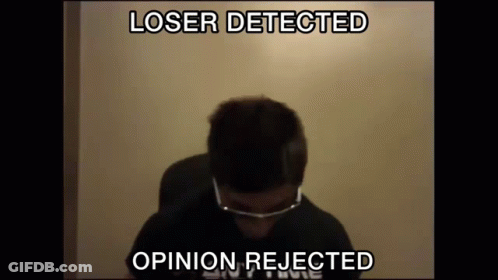 A Man Wearing Glasses Is Sitting In Front Of A Wall With The Words Loser Detected Opinion Rejected Above Him GIF