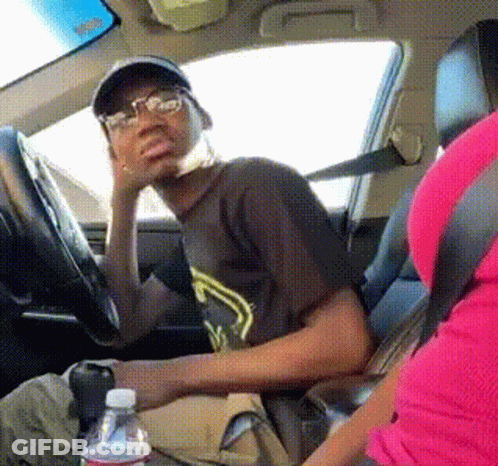 A Man Wearing Glasses Is Sitting In The Driver 'S Seat Of A Car Next To A Bottle Of Water GIF