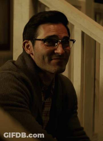 A Man Wearing Glasses Is Sitting On A Set Of Stairs And Smiling GIF