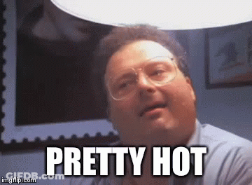 A Man Wearing Glasses Is Sitting Under A Light And Says `` Pretty Hot '' . GIF