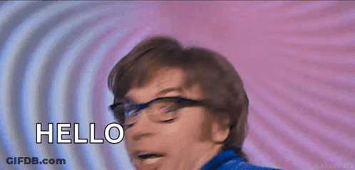 A Man Wearing Glasses Is Smiling And Saying Hello . GIF