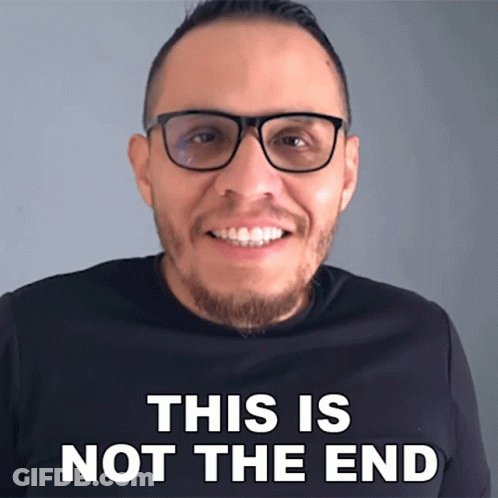 A Man Wearing Glasses Is Smiling In Front Of A Sign That Says " This Is Not The End " GIF