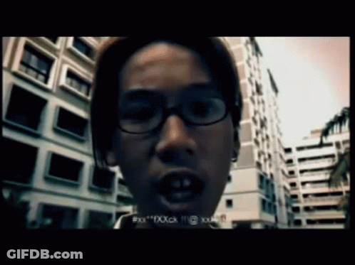 A Man Wearing Glasses Is Standing In Front Of A Building And Says " Xxx " GIF
