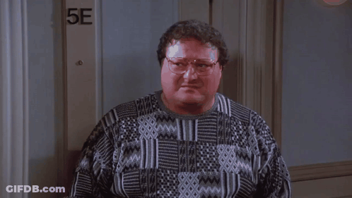 A Man Wearing Glasses Is Standing In Front Of A Door That Says 5E . GIF