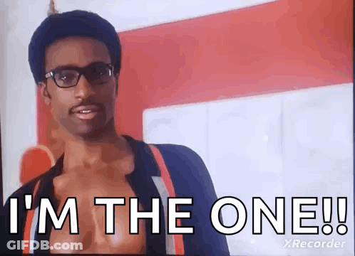 A Man Wearing Glasses Is Standing In Front Of A Red Wall And Says `` I 'M The One ! '' GIF