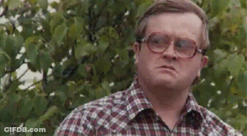 A Man Wearing Glasses Is Standing In Front Of A Tree . GIF