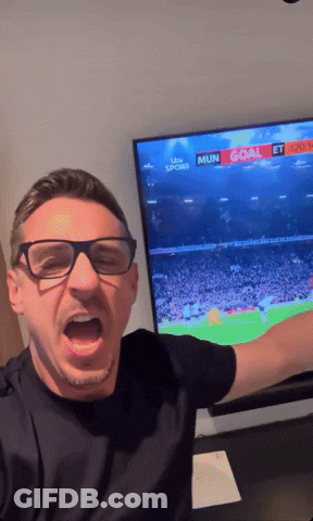 A Man Wearing Glasses Is Standing In Front Of A TV That Says ' Mun Goal ' On It GIF