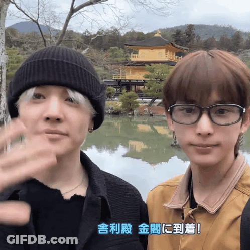 A Man Wearing Glasses Is Standing Next To Another Man Wearing A Beanie GIF