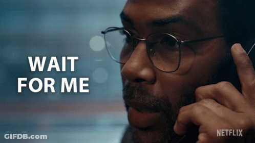 A Man Wearing Glasses Is Talking On A Cell Phone And The Words Wait For Me Are Behind Him GIF