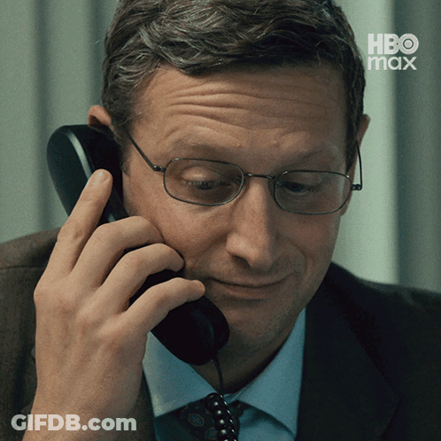 A Man Wearing Glasses Is Talking On A Telephone With Hbo Max Written On The Bottom GIF