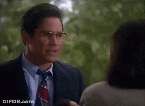 A Man Wearing Glasses Is Talking To A Woman GIF