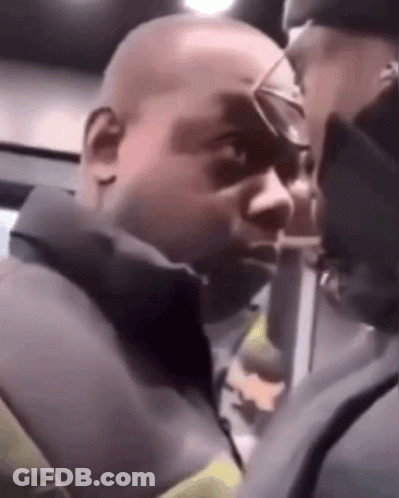 A Man Wearing Glasses Is Talking To Another Man In A Dark Room . GIF