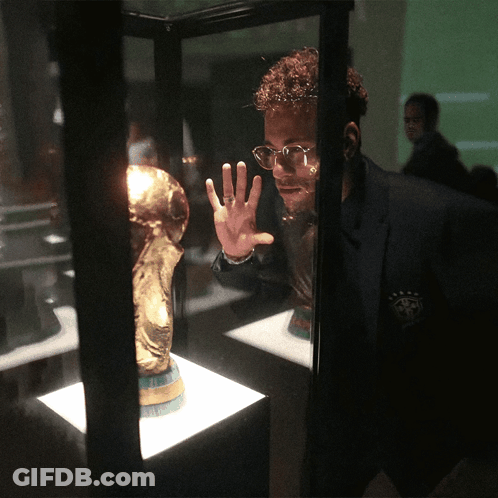 A Man Wearing Glasses Looks At A Trophy In A Case GIF