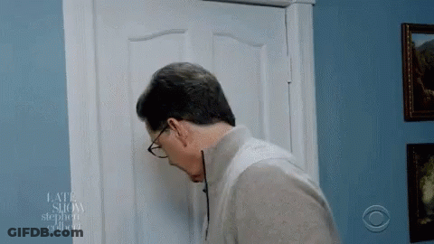A Man Wearing Glasses Looks Through A Door That Says Late Show On It GIF