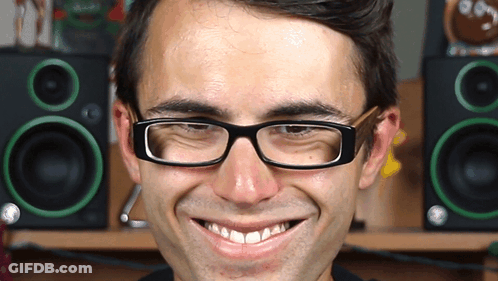 A Man Wearing Glasses Makes A Funny Face In Front Of Green Speakers GIF