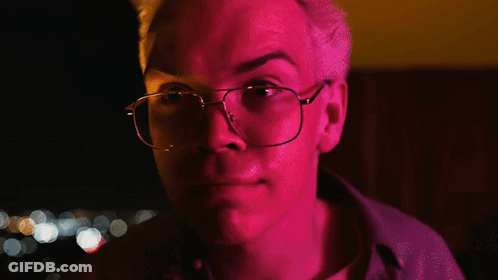 A Man Wearing Glasses Says Fair Enough In A Dark Room GIF