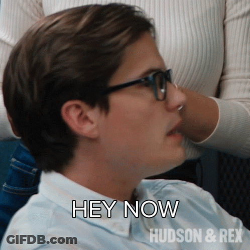 A Man Wearing Glasses Says " Hey Now " In Front Of A Woman GIF