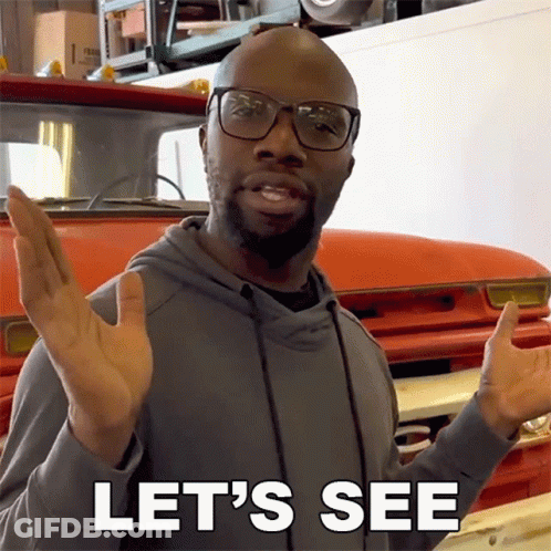 A Man Wearing Glasses Says Let 'S See While Standing In Front Of A Red Truck GIF