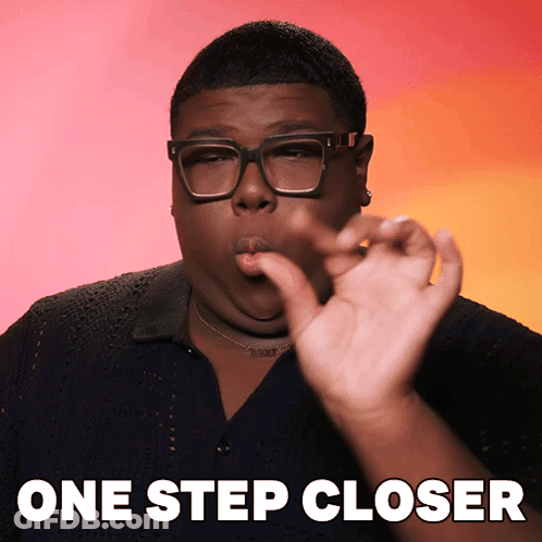 A Man Wearing Glasses Says One Step Closer With His Hand GIF