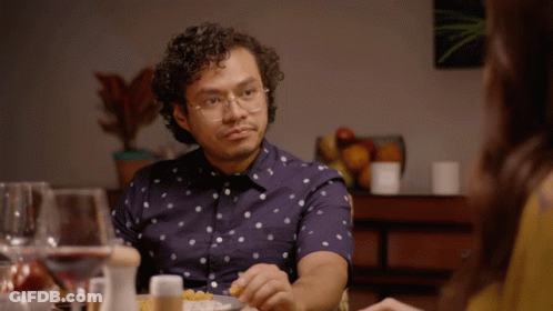 A Man Wearing Glasses Sits At A Table Eating Food GIF