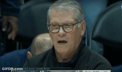 A Man Wearing Glasses Sits In The Stands Watching A Basketball Game GIF