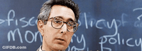 A Man Wearing Glasses Stands In Front Of A Blackboard That Says " Fiscal Theory " GIF