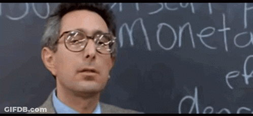 A Man Wearing Glasses Stands In Front Of A Blackboard That Says Moneta GIF