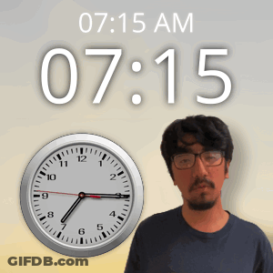A Man Wearing Glasses Stands In Front Of A Clock That Says 7:15 GIF