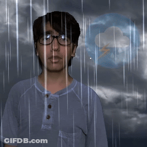 A Man Wearing Glasses Stands In Front Of A Cloud And Lightning Bolt GIF