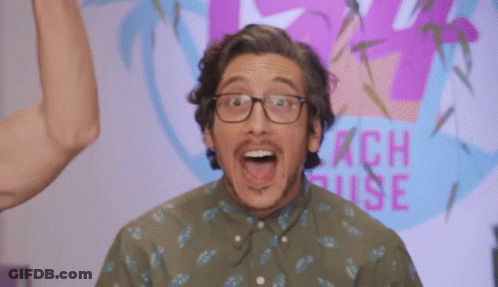 A Man Wearing Glasses Stands In Front Of A Peach House Sign GIF