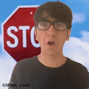A Man Wearing Glasses Stands In Front Of A Red Stop Sign GIF