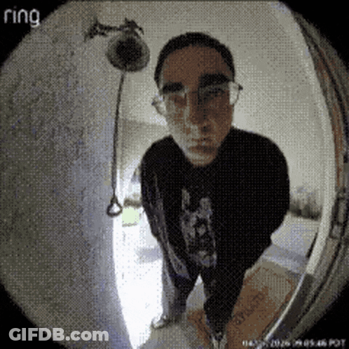 A Man Wearing Glasses Stands In Front Of A Ring Doorbell Camera GIF