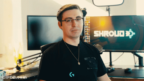 A Man Wearing Glasses Stands In Front Of A Shroud Sign GIF
