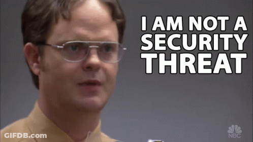 A Man Wearing Glasses Stands In Front Of A Sign That Says I Am Not A Security Threat GIF