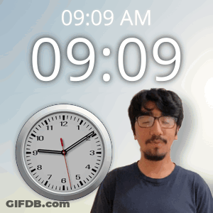 A Man Wearing Glasses Stands In Front Of A Wall Clock That Says 9:09 Am GIF
