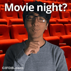 A Man Wearing Glasses Stands In Front Of Rows Of Red Seats With The Words Movie Night Written Above Him GIF