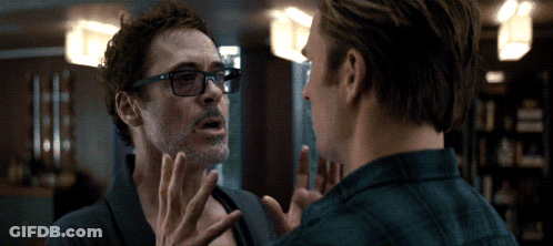 A Man Wearing Glasses Talks To Another Man In A Room GIF