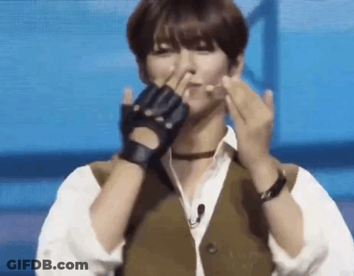 A Man Wearing Gloves And A Vest Is Making A Heart With His Hands . GIF